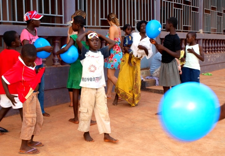 Ghanaian children playing a game with a white volunteer